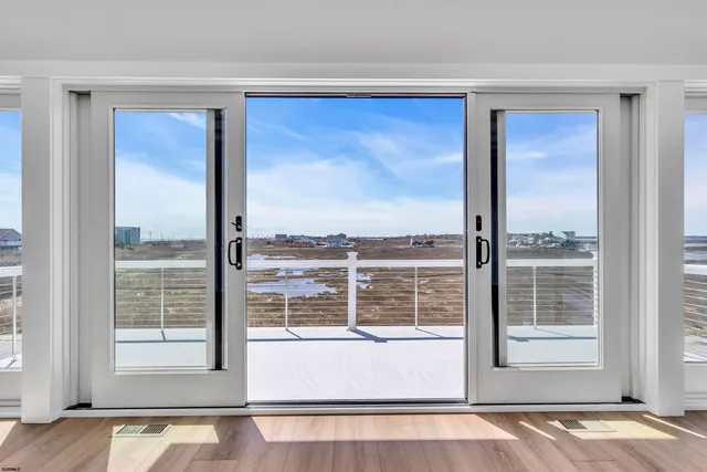 a large kitchen with stainless steel appliances a large counter top a stove a refrigerator with white cabinets and wooden floor