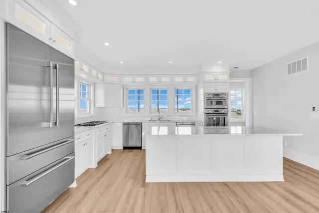 a kitchen with granite countertop white cabinets stainless steel appliances and a window