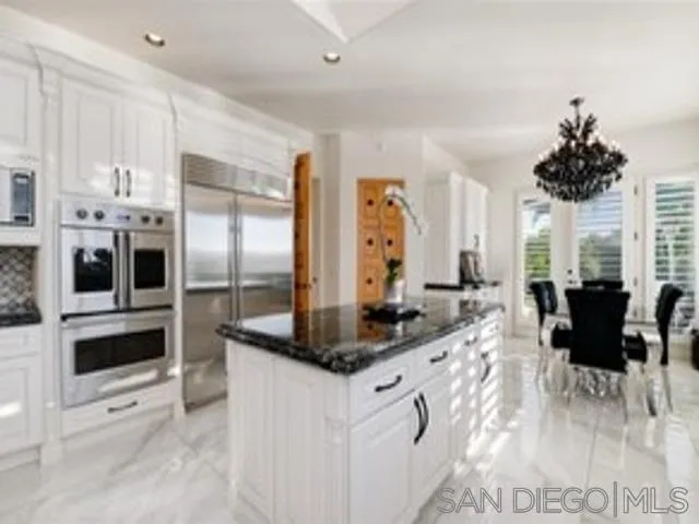 17381 Circa Oriente Rancho Santa Fe, CA 92067 - Photo 3 of 37 a kitchen with stainless steel appliances kitchen island granite countertop a refrigerator a stove and white cabinets with wooden floor