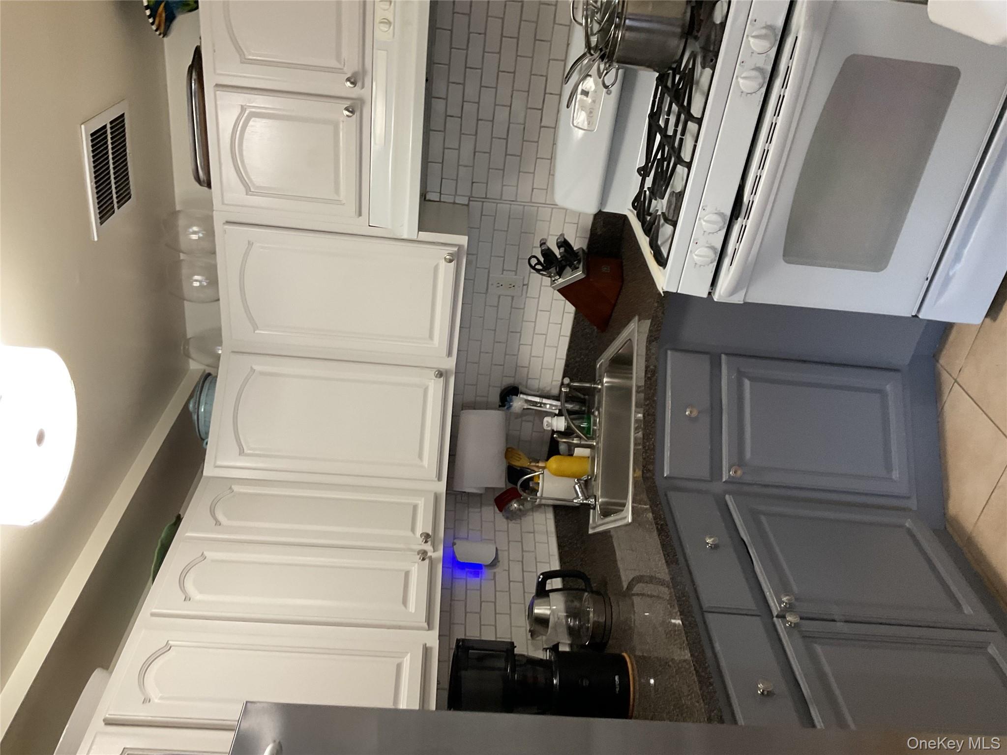 175 Beach 29th Street Queens, NY 11691 - Photo 19 of 21 Kitchen featuring stove, gray cabinetry, and white cabinetry