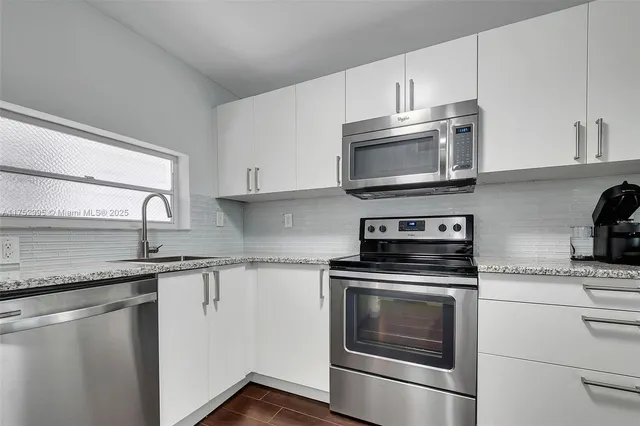 a kitchen with granite countertop white cabinets and stainless steel appliances