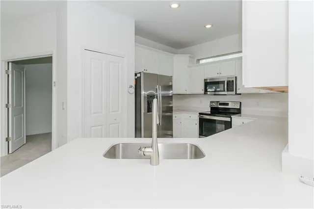 a kitchen with stainless steel appliances kitchen island granite countertop a refrigerator and a sink