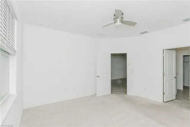 an empty room with a ceiling fan and a window