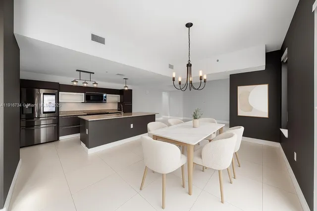 a kitchen with stainless steel appliances kitchen island granite countertop a sink dishwasher a stove a refrigerator with a dining table and chairs