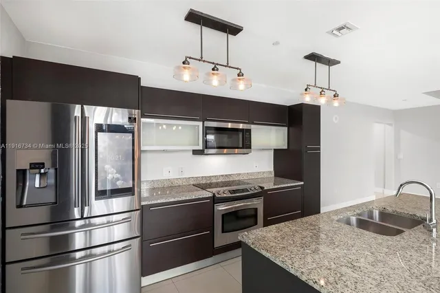 a kitchen with stainless steel appliances granite countertop a refrigerator and a stove top oven