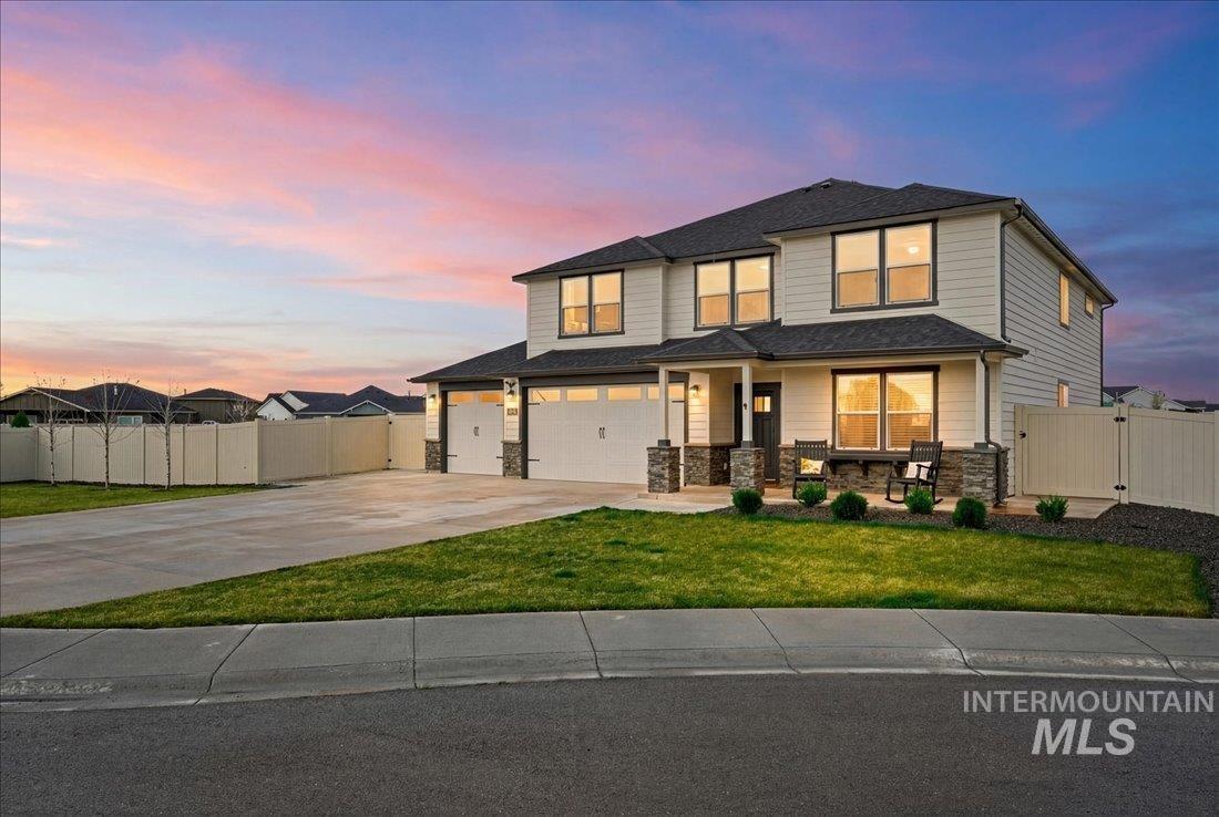 View of front of house featuring a gate, covered porch, driveway, an attached garage, and stone siding