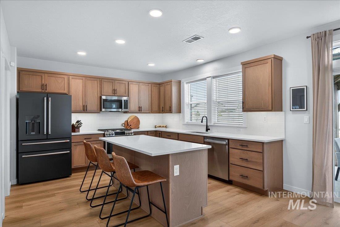 1993 North Perth Court Middleton, ID 83644 - Photo 3 of 45 Kitchen featuring stainless steel appliances, light wood finished floors, a kitchen island, wood finish cabinetry, and recessed lighting