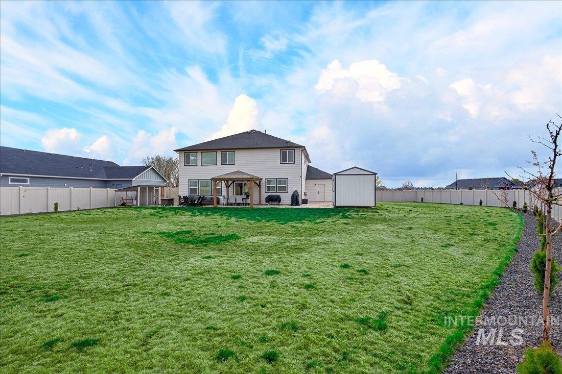 1993 North Perth Court Middleton, ID 83644 - Photo 40 of 45 Rear view of house featuring a gazebo, a patio, a fenced backyard, and a storage shed