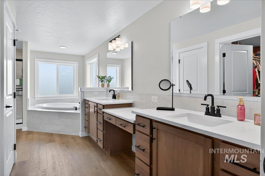 1993 North Perth Court Middleton, ID 83644 - Photo 5 of 45 Full bathroom with double vanity, light wood-style floors, a garden tub, a textured ceiling, and a spacious closet