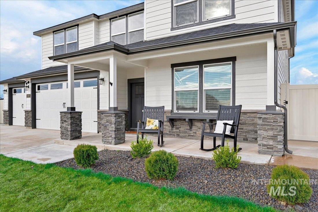 1993 North Perth Court Middleton, ID 83644 - Photo 10 of 45 Rear view of property featuring stone siding, a porch, a garage, and driveway
