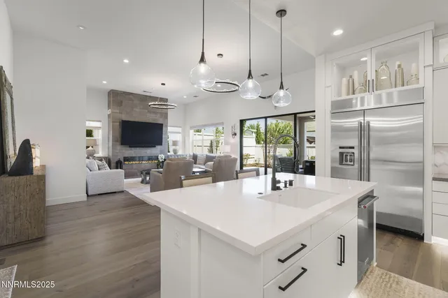a kitchen with stainless steel appliances a stove a sink a kitchen island with couches and flat screen tv