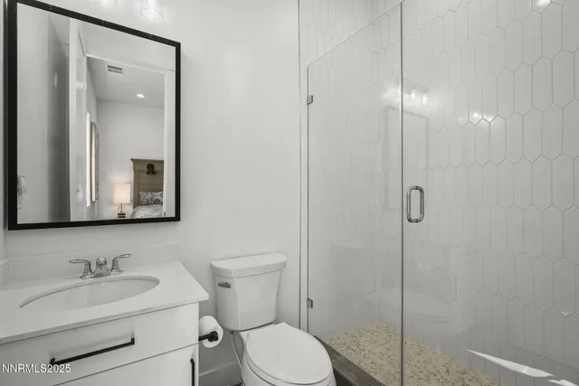 a bathroom with a toilet sink vanity granite and mirror