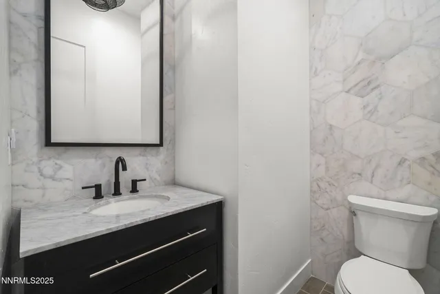 a bathroom with a granite countertop sink and a toilet