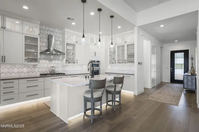 a kitchen with stainless steel appliances kitchen island granite countertop a table chairs sink and cabinets