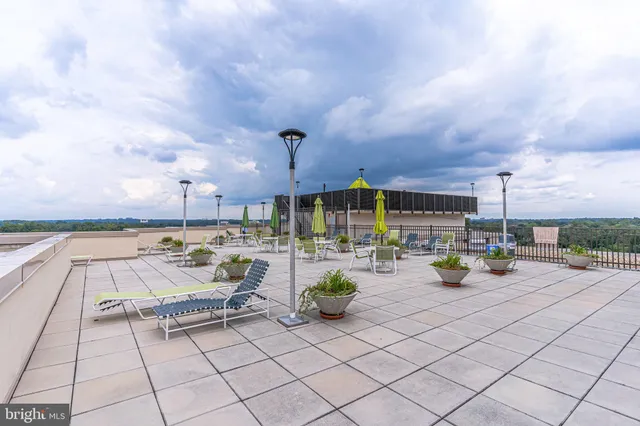 a view of roof deck with dining table and chairs with potted plants