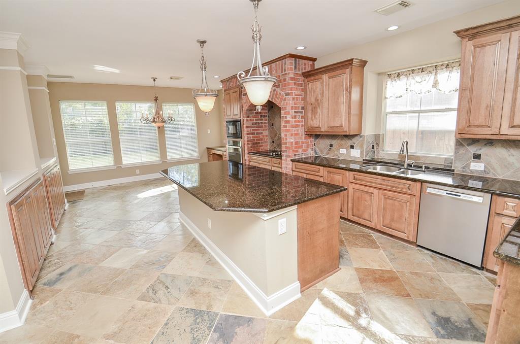 a large kitchen with kitchen island granite countertop a sink a counter top space appliances and cabinets