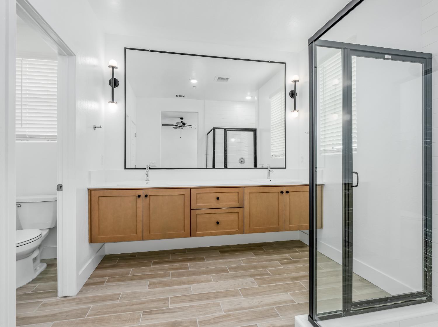 2734 East Teaberry Drive Fresno, CA 93730 - Photo 26 of 34 a bathroom with a granite countertop sink mirror and a shower