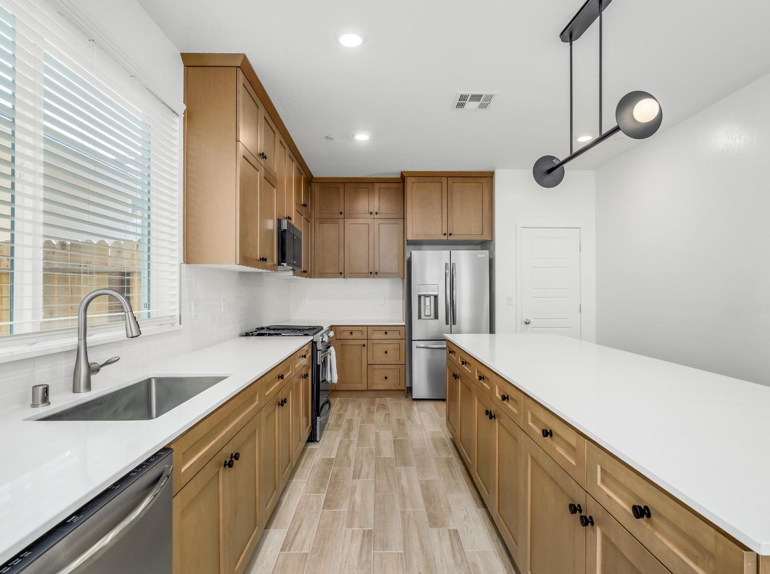 2734 East Teaberry Drive Fresno, CA 93730 - Photo 8 of 34 a large kitchen with a sink and dishwasher a stove top oven with wooden floor