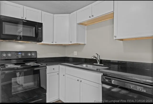 a kitchen with granite countertop white cabinets stainless steel appliances and a sink