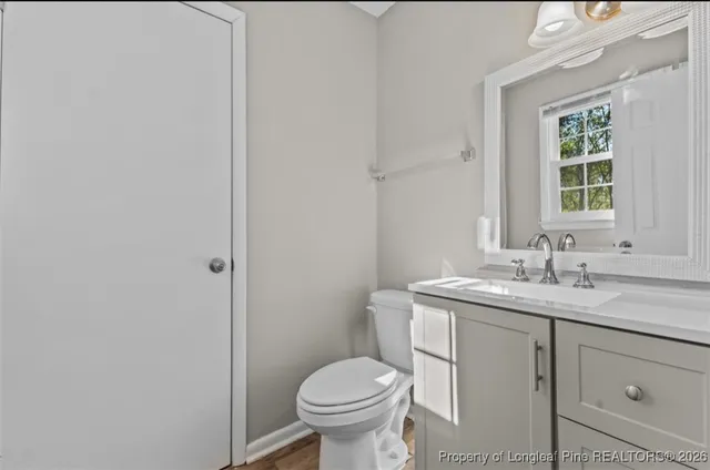 a bathroom with a granite countertop toilet a sink and a window