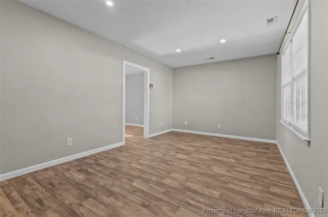a view of an empty room with wooden floor and a window