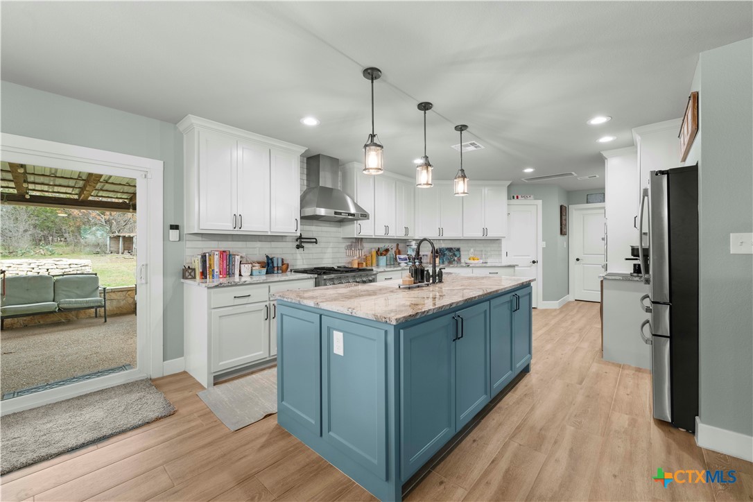 8901 Brewer Lane Salado, TX 76571 - Photo 13 of 30 a kitchen with kitchen island granite countertop a refrigerator oven a sink dishwasher and white cabinets with wooden floor