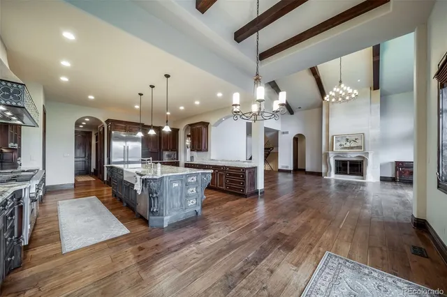 a large living room with kitchen island a flat screen tv a stove and a wooden floor
