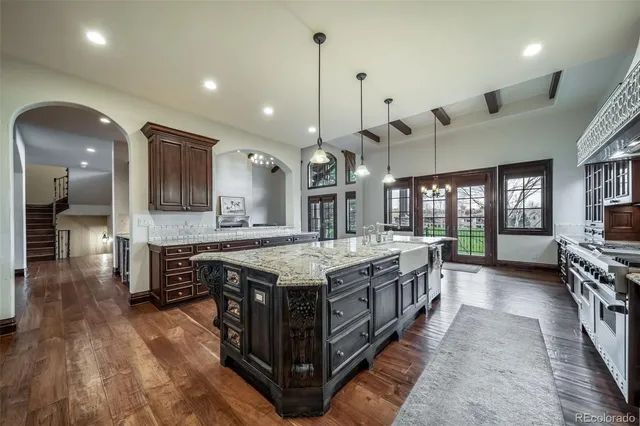 a large kitchen with stainless steel appliances granite countertop a stove and a wooden floors