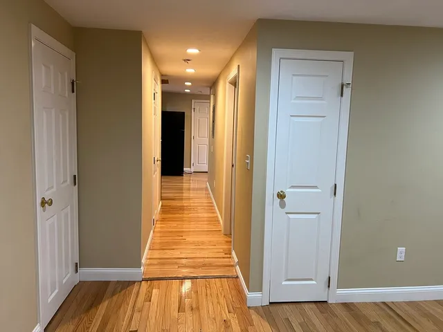 a view of a hallway with wooden floor and a bathroom