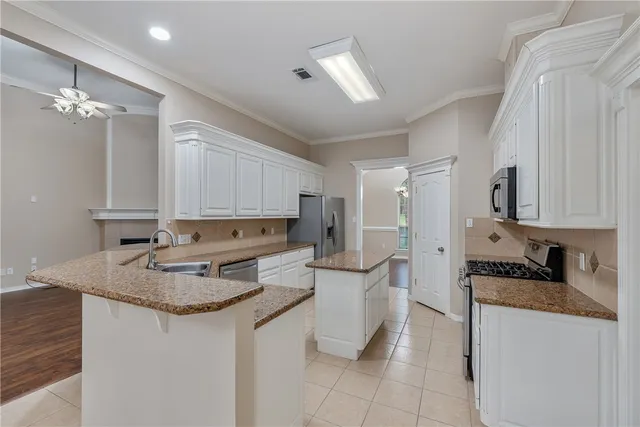 a kitchen with kitchen island granite countertop a sink cabinets and refrigerator