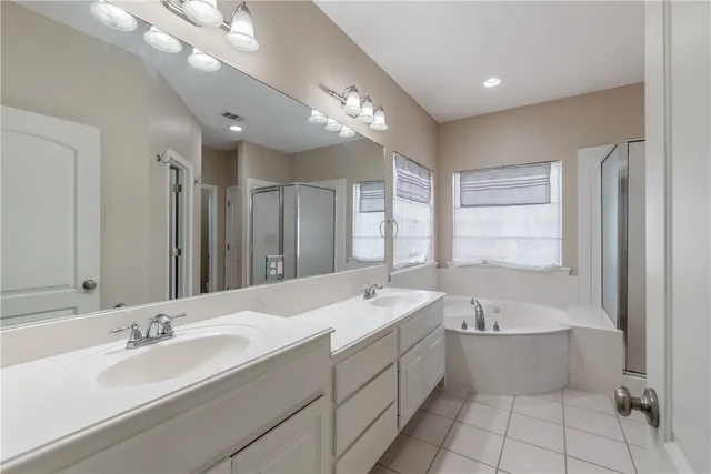 a spacious bathroom with a bathtub shower sink double and mirror