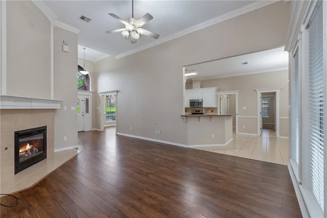 a view of a kitchen and an empty room with wooden floor and a fireplace