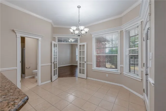 a view of an empty room with window and chandelier