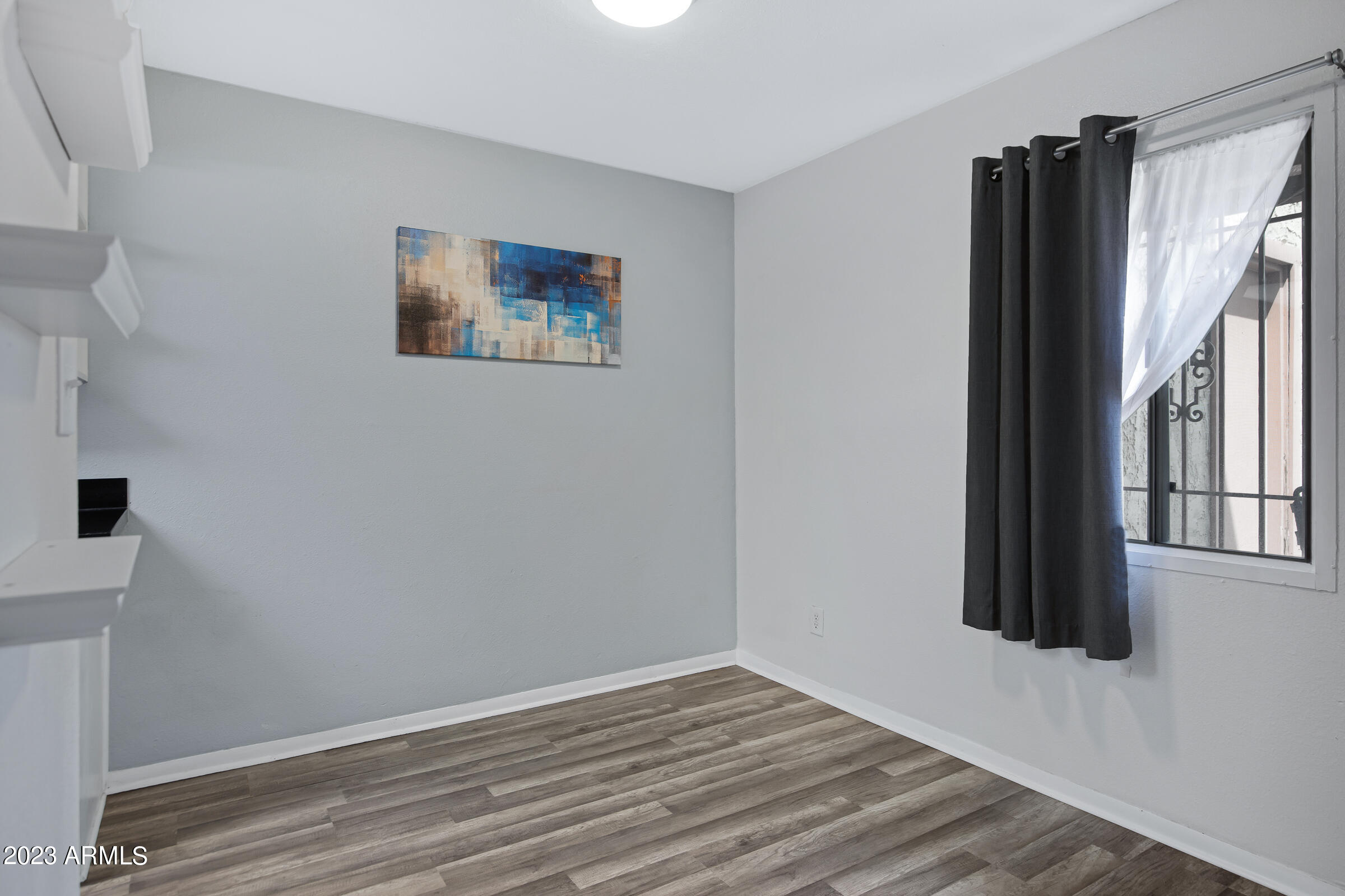 948 South Alma School Road, Unit 147 Mesa, AZ 85210 - Photo 12 of 22 a view of an empty room with wooden floor and a window