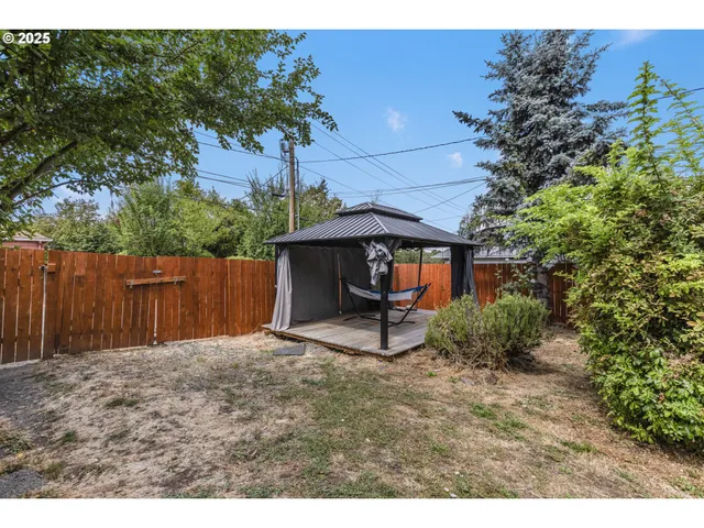 a view of a backyard with plants and a bench