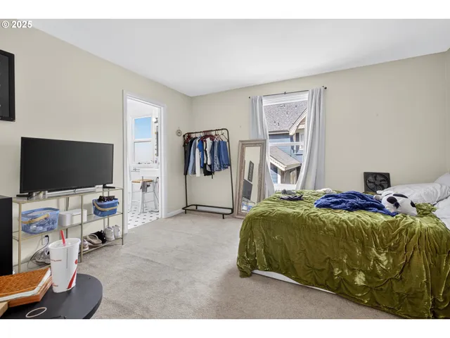a bedroom with a bed and a flat tv screen on the dresser