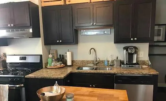 a kitchen with granite countertop a sink a stove and cabinets