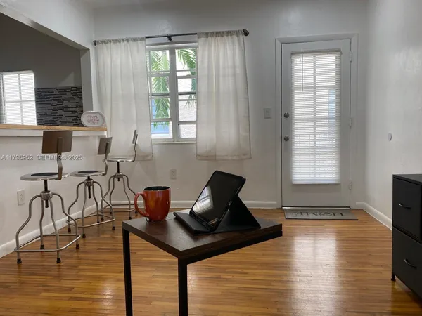 a living room with table chairs and wooden floor