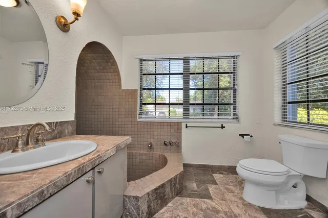 a spacious bathroom with a granite countertop sink a toilet and a window