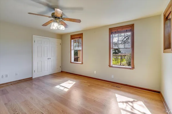 a view of an empty room with a window and wooden floor