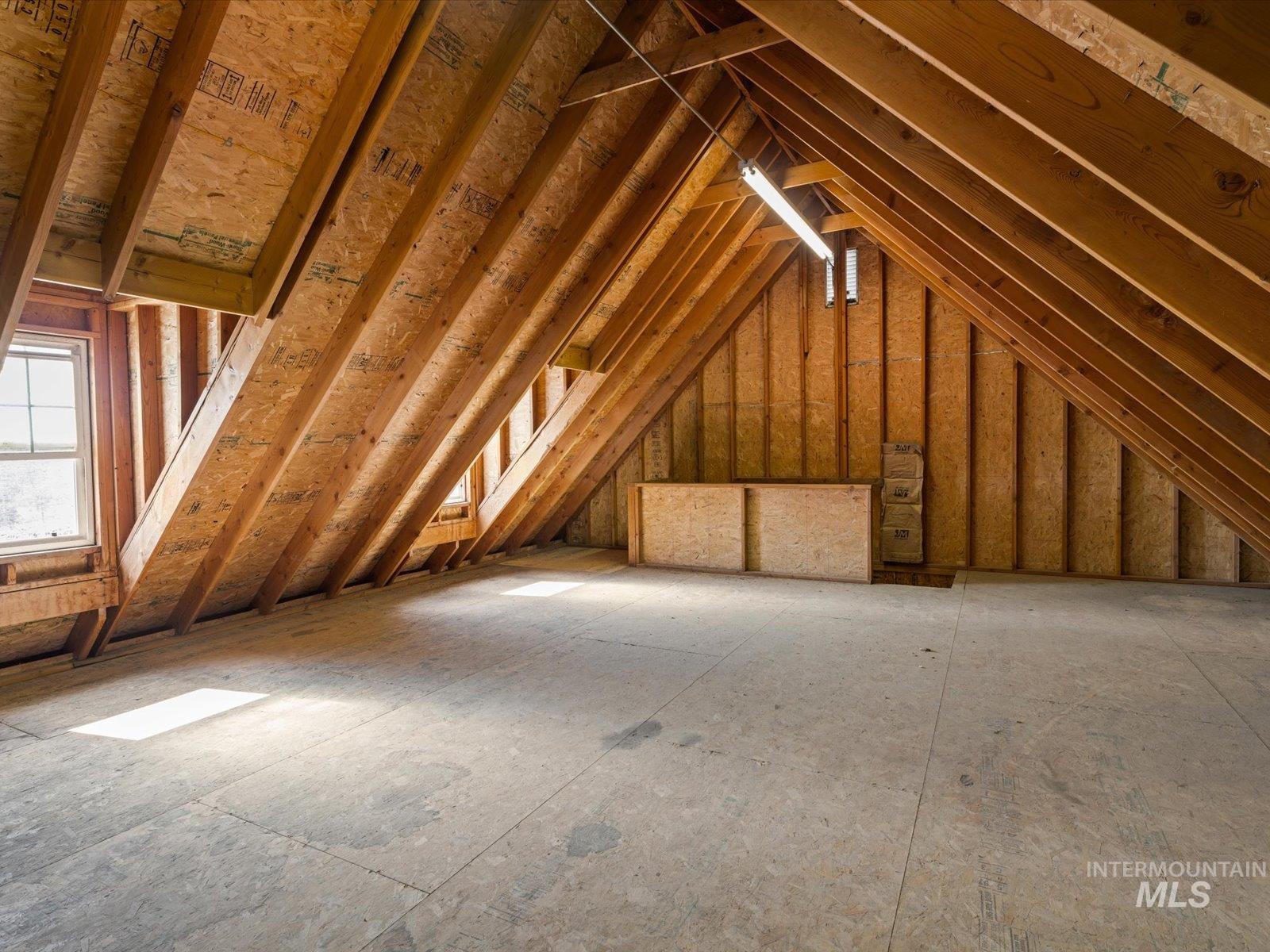 3540 Wills Road Emmett, ID 83617 - Photo 30 of 36 Spacious unfinished attic space featuring exposed wood rafter framing, plywood flooring, and multiple windows for natural light