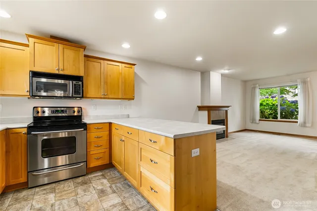 a kitchen with stainless steel appliances granite countertop a refrigerator a stove and a sink with wooden floor