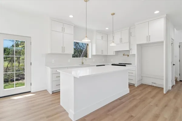 a kitchen with white cabinets and window