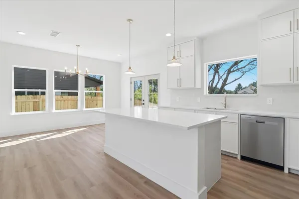 a kitchen with stainless steel appliances granite countertop a stove a sink and white cabinets with wooden floor
