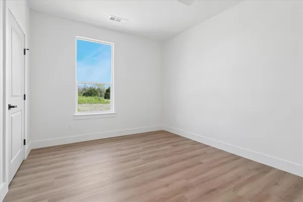 an empty room with wooden floor and window