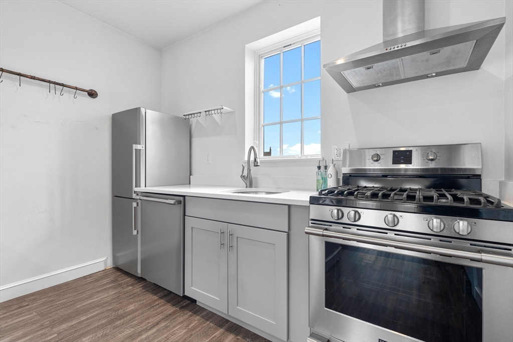 105 Broadway, Unit 2 Chelsea, MA 02150 - Photo 7 of 9 a kitchen with stainless steel appliances white cabinets and a stove top oven