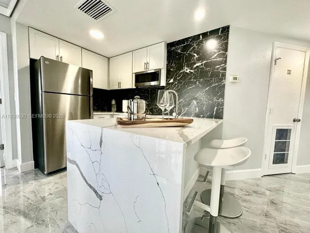 a kitchen with stainless steel appliances kitchen island granite countertop a refrigerator and a stove top oven