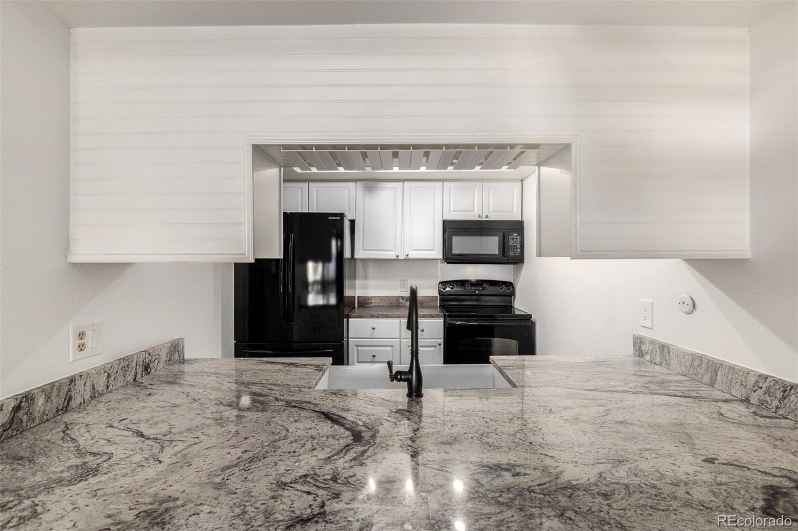 4896 South Dudley Street, Unit 910 Littleton, CO 80123 - Photo 5 of 30 a kitchen with stainless steel appliances kitchen island granite countertop a stove and a refrigerator