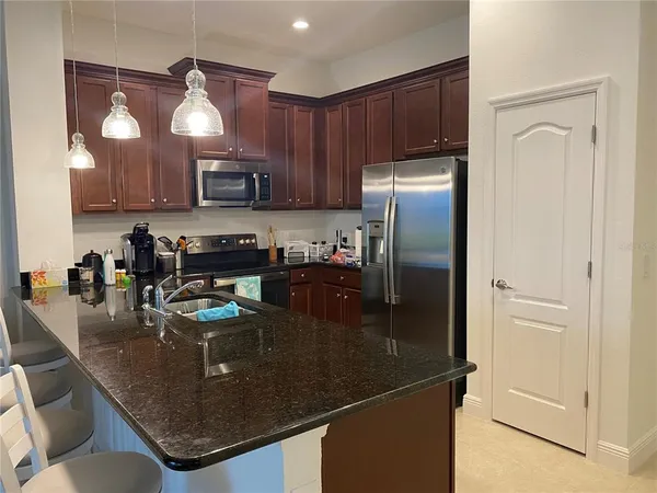 a kitchen with stainless steel appliances granite countertop a refrigerator a stove a sink a microwave and a refrigerator