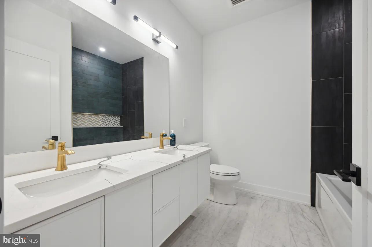 8201 Shawnee Street Philadelphia, PA 19118 - Photo 16 of 22 a bathroom with a double vanity sink toilet and mirror